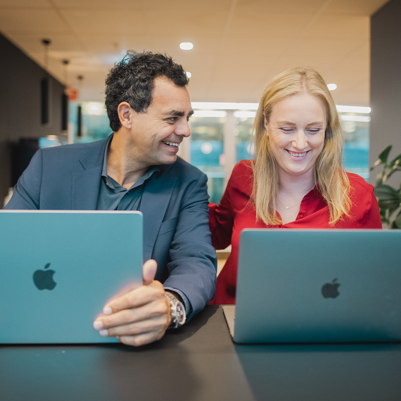 Två personer sitter vid sina laptops och pratar