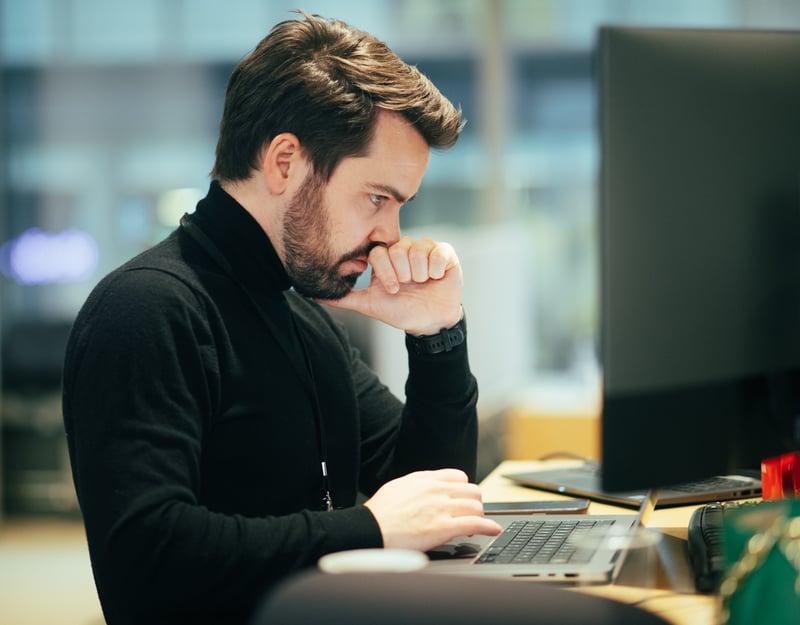 Portrett av en mann som sitter foran en PC og ser konsentrert ut