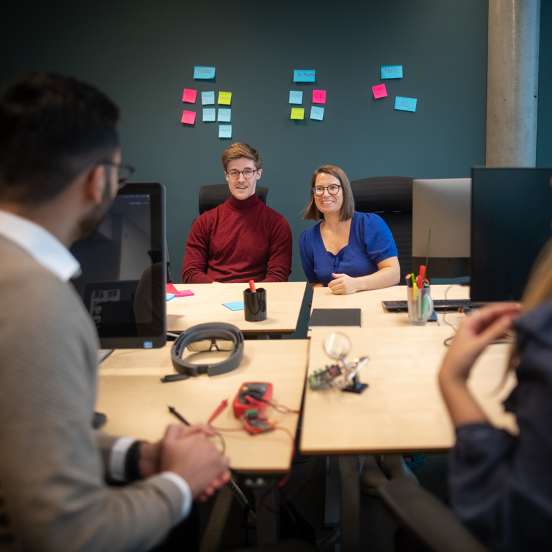 Personer sitter runt ett konferensbord och ler