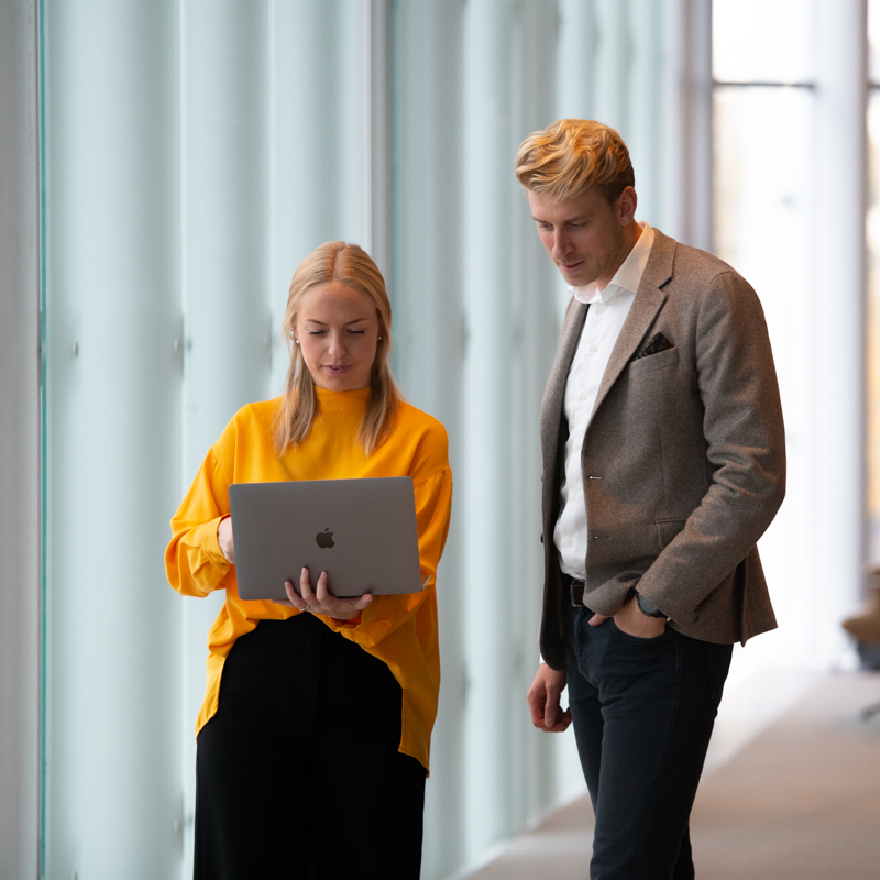 Man och kvinna står och tittar på laptop